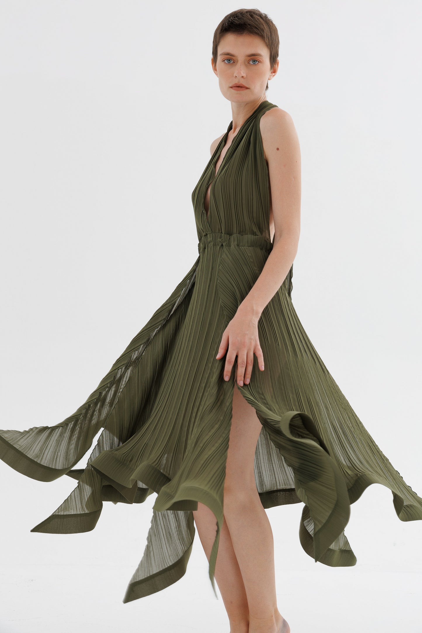 Woman wearing a green dress with a slit on a white background
